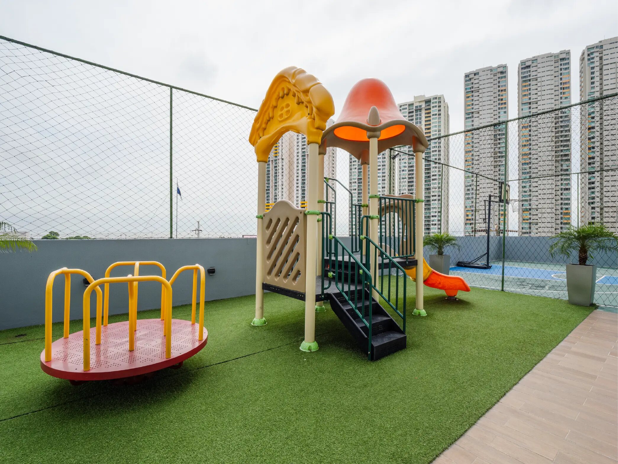 Área de juegos infantil al aire libre con resbaladilla y vista de torres.