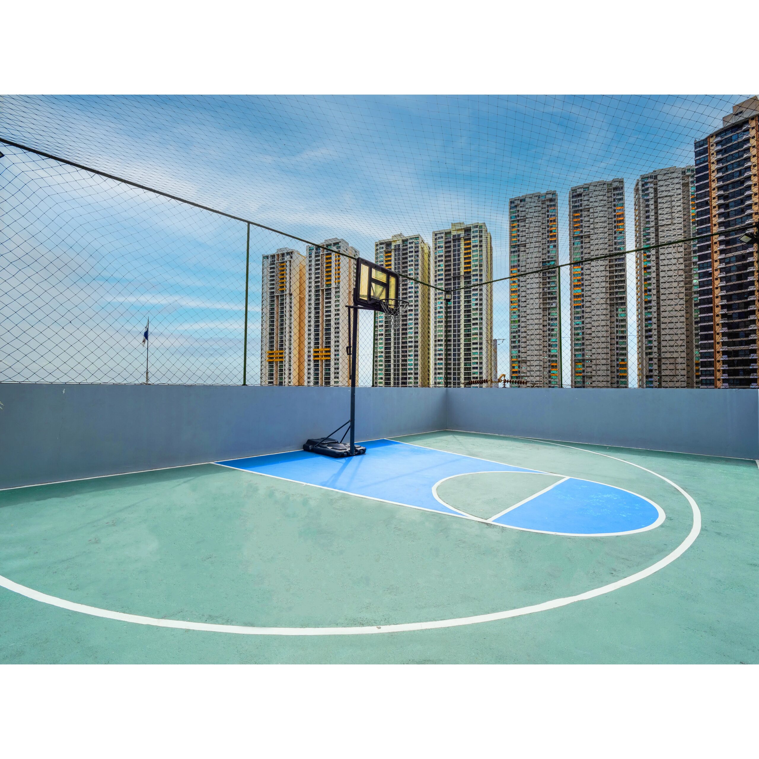 Cancha de baloncesto al aire libre con vista a torres residenciales.