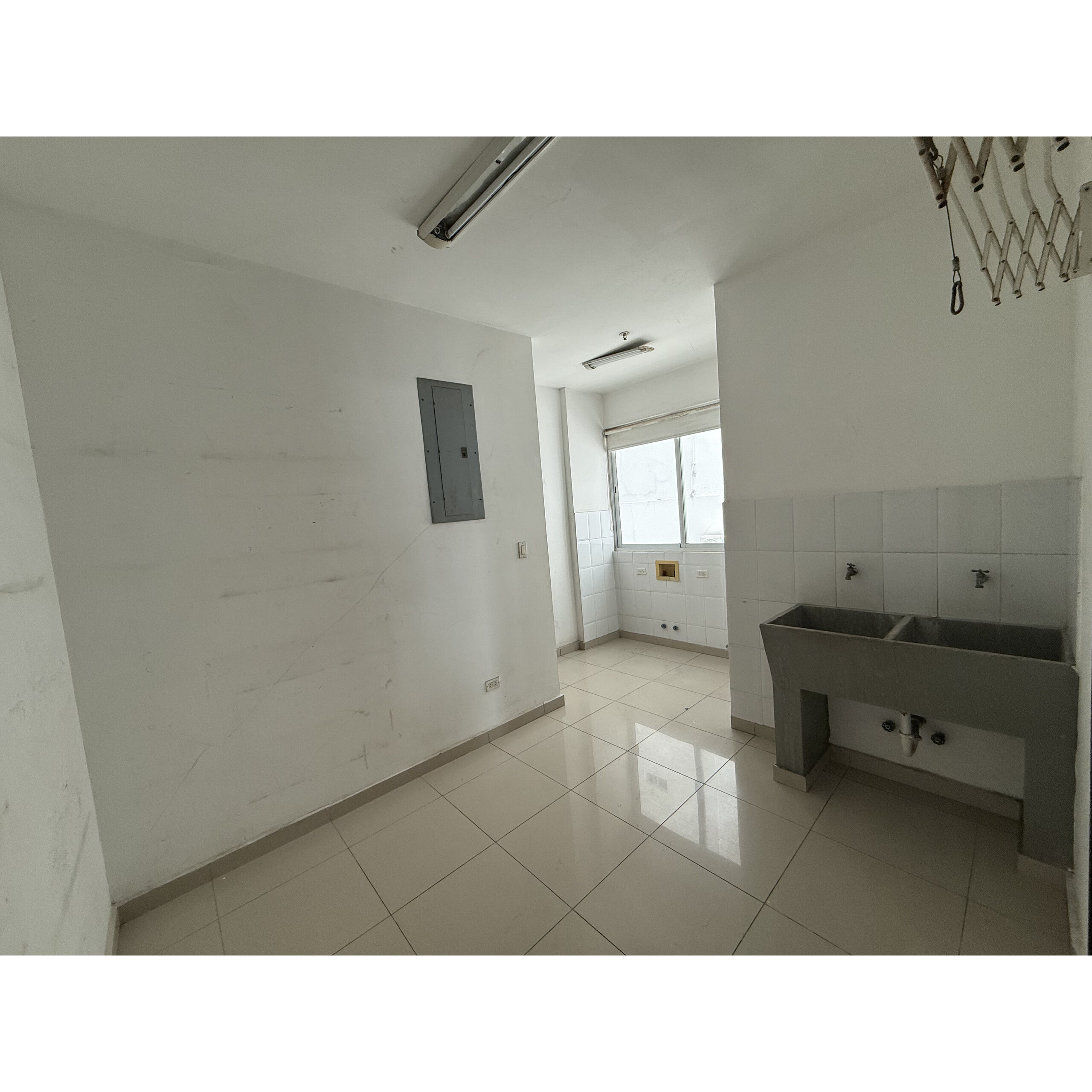 Lavandería interior con fregadero de acero, ventanas y piso de baldosas.