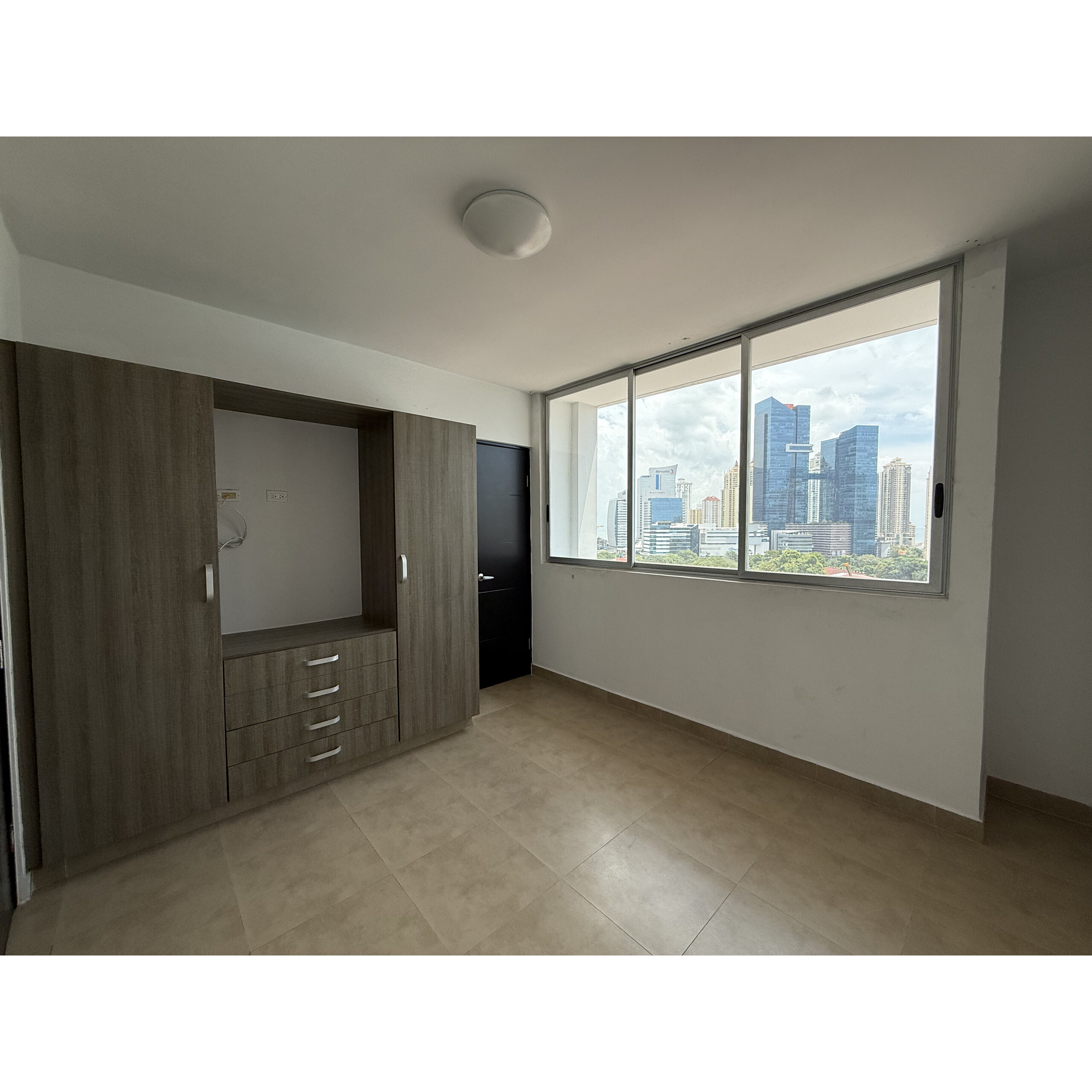 Recámara vacía con clóset empotrado y ventana grande con vista urbana.