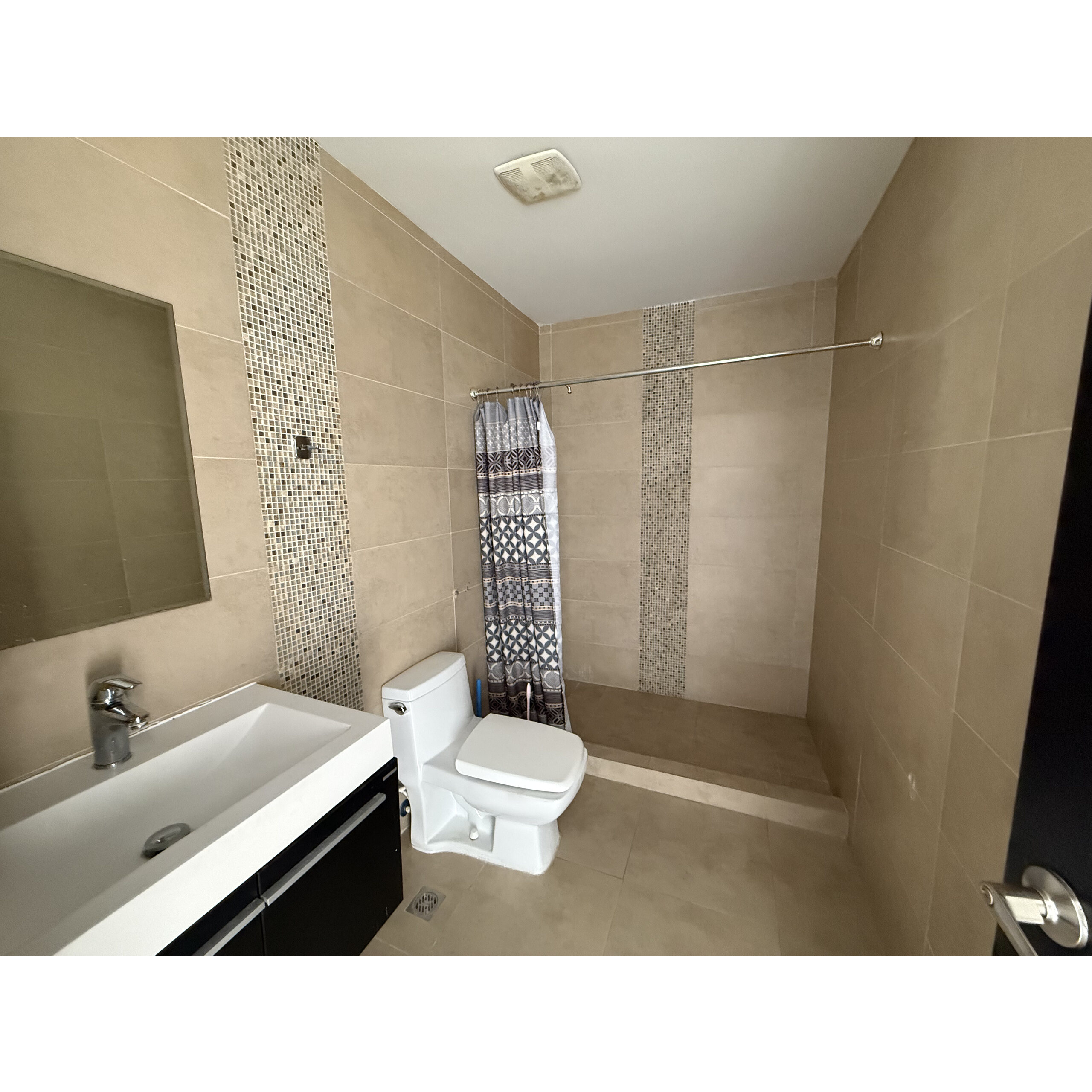 Baño con lavabo, inodoro y regadera con cortina.